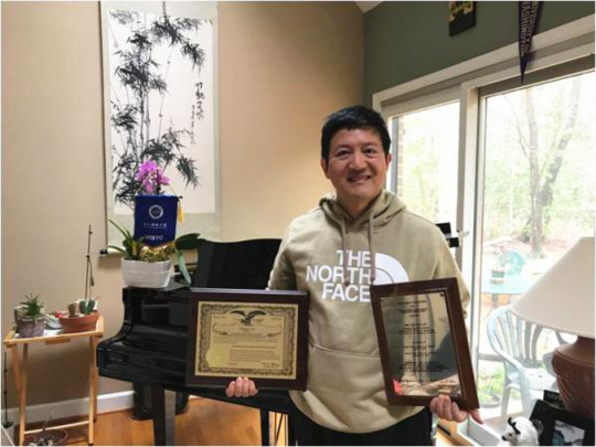 刘朝宇手拿美国专利证书（左）和田纳西大学颁发的获奖证书（图据电子科技大学网站）