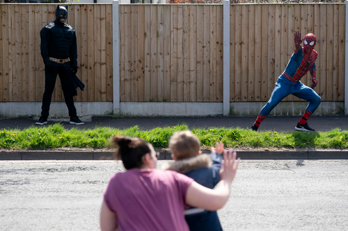  4月13日，在英国曼彻斯特，打扮成“蜘蛛侠”的表演者来到居民区表演。新华社发