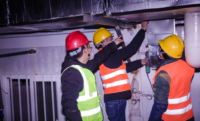 罗文浩（左一）在火神山现场指导工人进行通风管道安装