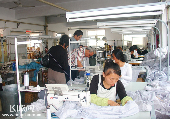 外商在华兴服装有限公司生产车间查看订单加工情况。资料图