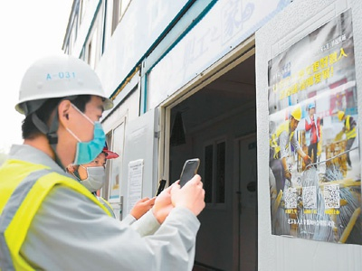 在北京市东城区一处施工工地，中建一局工人通过手机扫码了解《保障农民工工资支付条例》的相关情况。新华社记者 张晨霖摄