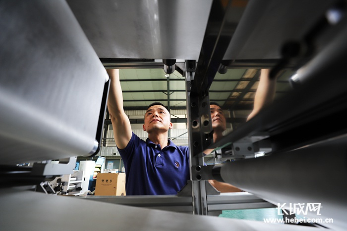 胡永杰在车间调试口罩机。李洋摄