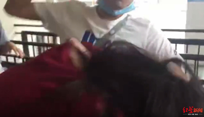 ↑视频显示，男子左手将红衣女子按住，右手捶打其背部