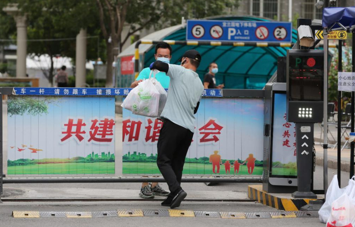 6月15日，北京新发地市场周边一小区出入口，居民领取代购的生活用品。