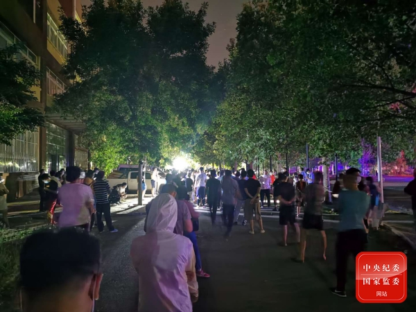  图为校区内间隔分散、排队等待检测的居民。