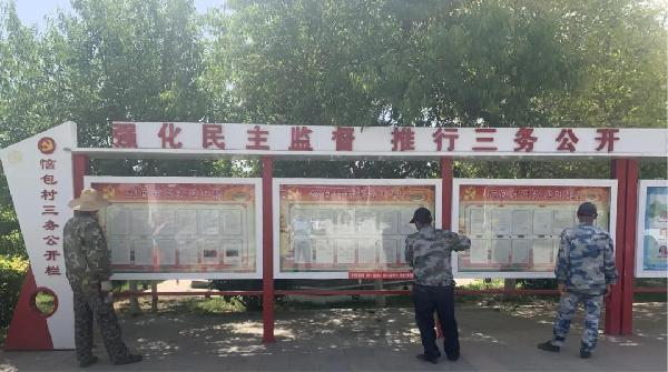 恼包村村民正在“三务”公开栏目前查看村务公开信息