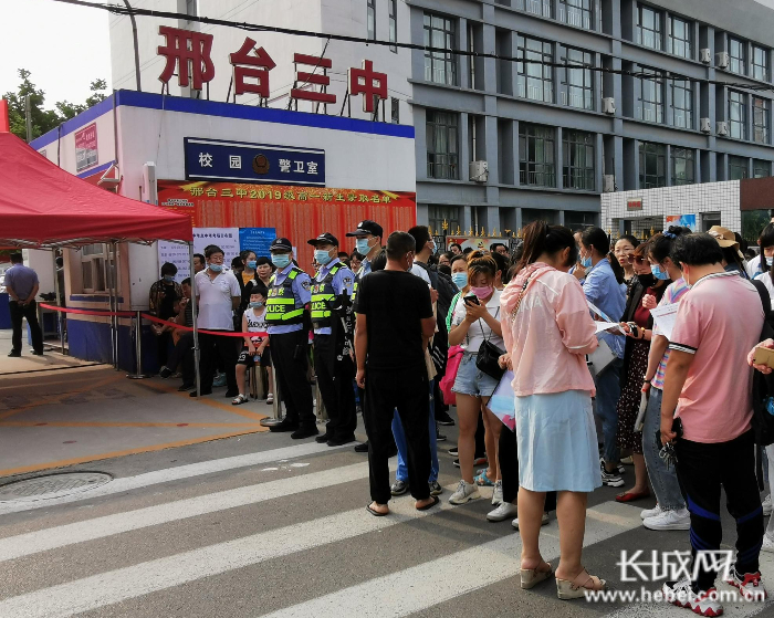 第三中学考点外，考生在排队等待入场，部分送考的家长也在等待开考。 魏亚慧 摄