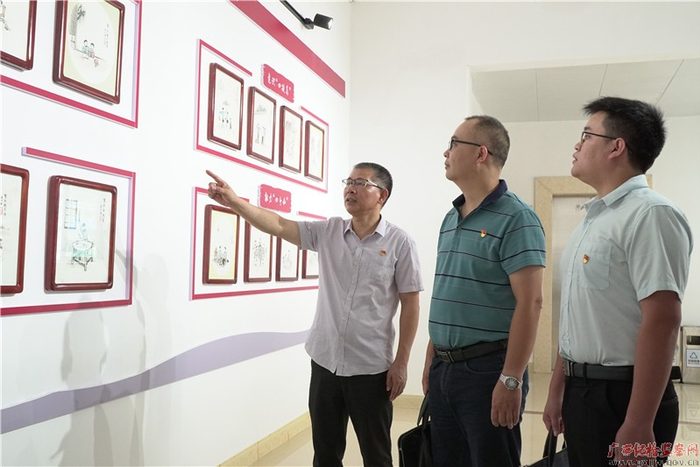 林柏江（左一）为党员干部讲解市纪委监委机关纪检监察干部素质提升24点要求漫画展