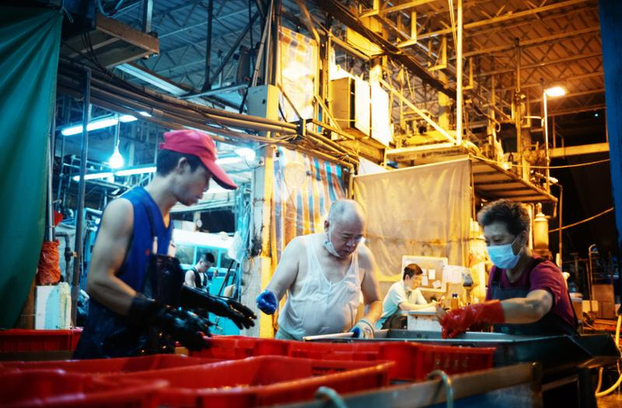 和工人们一起忙碌的李彩华（中）