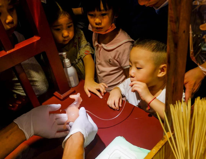 这位小朋友正在吹一个“小马”糖人