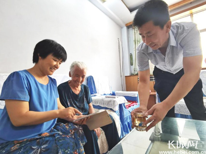 枣强市民范宁（左）与爱人魏朝攀教母亲使用数码产品与亲戚视频聊天。长城网记者 张梅胜 摄