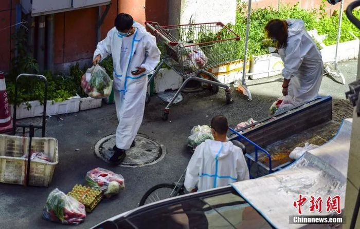 资料图：8月20日，新疆维吾尔自治区乌鲁木齐市的志愿者帮助居民购买和配送蔬菜、水果等生活必需品。 中新社记者 刘新 摄