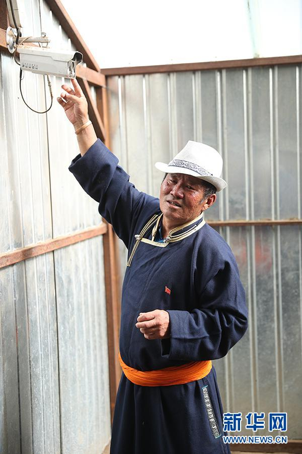 图为其日麦拉图介绍自家羊棚内监视器的使用方法。新华网记者焦鹏摄