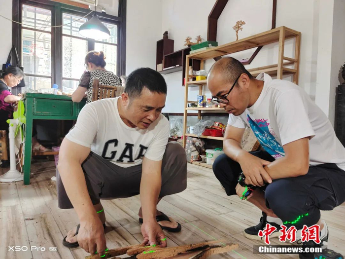 青年书画家何光明与软木画大师林世冰（左）一起探讨软木画创作工艺。受访者供图