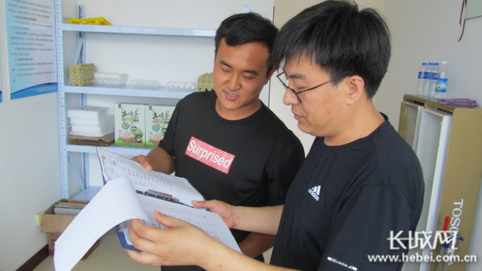刘强（右）在翻看高洪臣的销售记录。  长城网记者 郭庆敏 摄