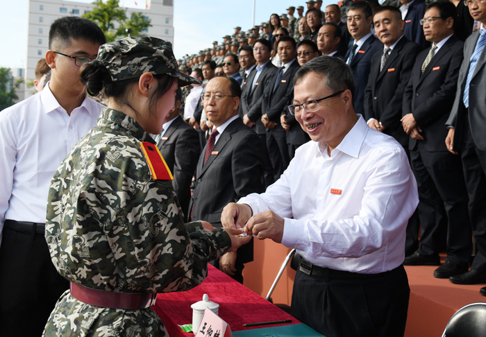 ▲校党委书记王仰麟为新生代表佩戴校徽