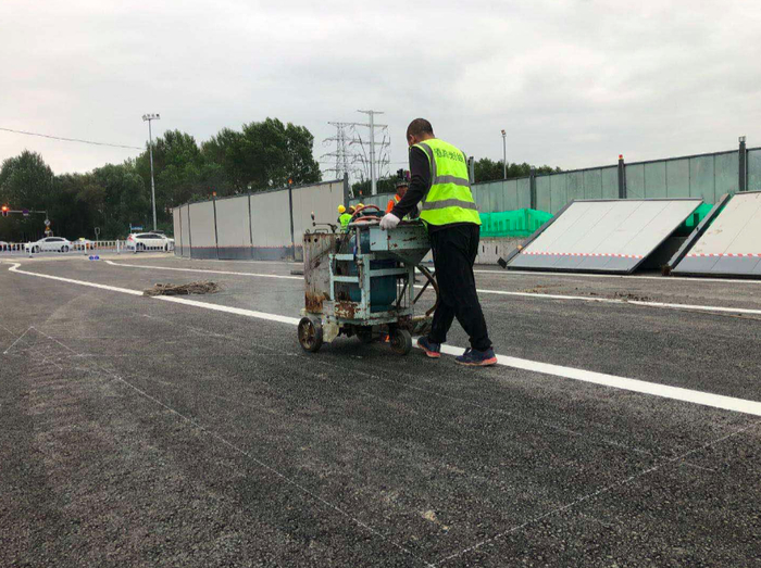 ▲道路标线施工人员正在给恢复后的蔚山路画道路标线