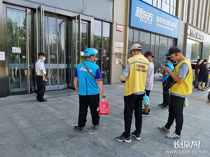 万达广场写字楼C座，七八个外卖员拿着外卖等待顾客下来取餐。长城网记者 周亚彬 摄