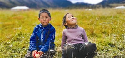 　　在杂多县昂赛乡年都村，5岁的的藏族小女孩才音措瓦正目不转睛地盯着采访团用来拍摄的无人机，在她身旁是哥哥色萨。刘露霏摄