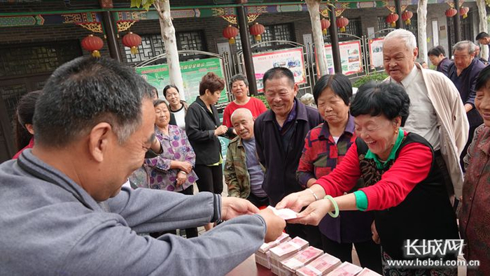 东街村“两委”干部为60岁以上老人发放养老金，老人拿到养老金后笑得合不拢嘴。长城网记者 吴新光 摄