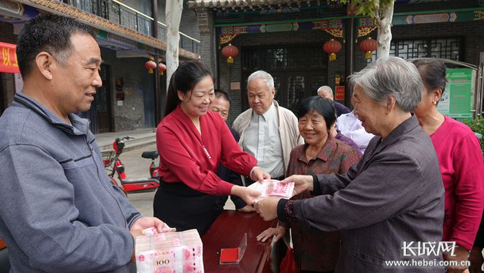 东街村“两委”干部为60岁以上老人发放养老金，老人拿到养老金后笑得合不拢嘴。长城网记者 吴新光 摄