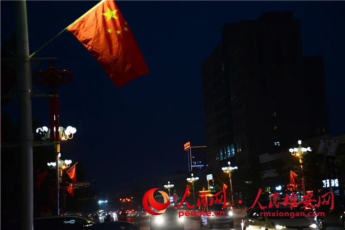 夜幕下的雄安新区国旗飘扬，灯光闪耀。朱峙委/摄