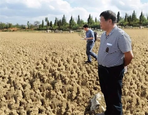▲ 2010 年 5 月，曹德旺在云南省陆良县天生坝水库考察旱情，干涸的土地已经完全龟裂。这一年，他为旱情严重的西南五省市捐款 2 亿元，该项捐款惠及 10 万户受灾家庭