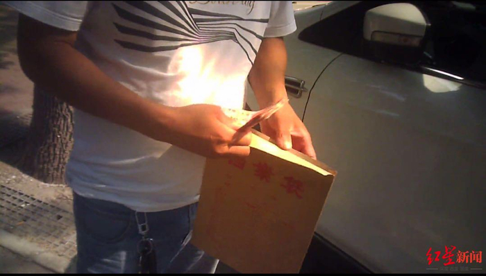 ▲与刘某某同样遭遇的邢某某等司机将2000元现金清点后，装进一档案袋中