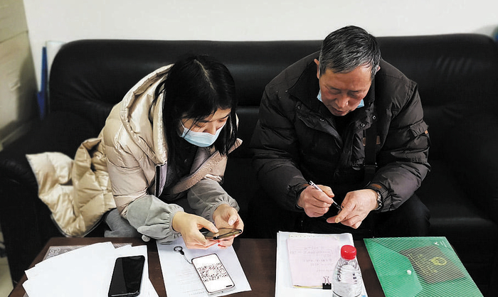 都江堰市医保局工作人员（左一）指导谢婆婆的儿子申请长期照护保险