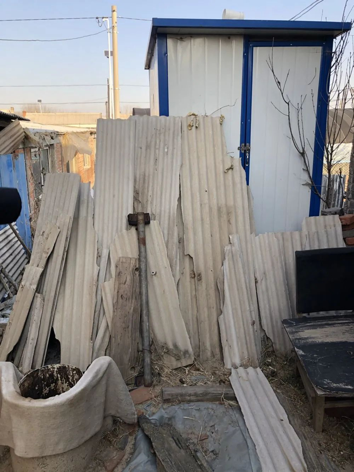 厕所前堆满了木板、秸秆等杂物，年逾八旬的村民用前面的铁桶“方便”。新华社记者 于也童摄