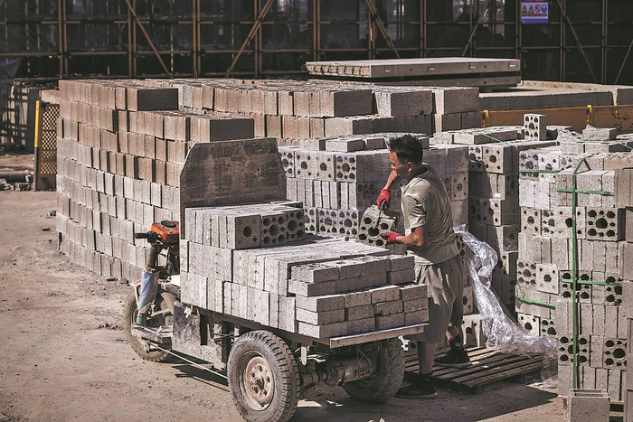 高温下，未戴安全帽的工人在项目工地搬运防火建材。