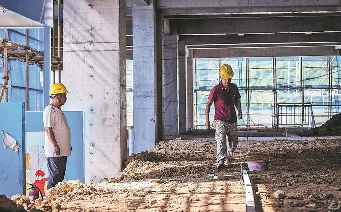 图为一位安全员督促工人正确佩戴安全帽