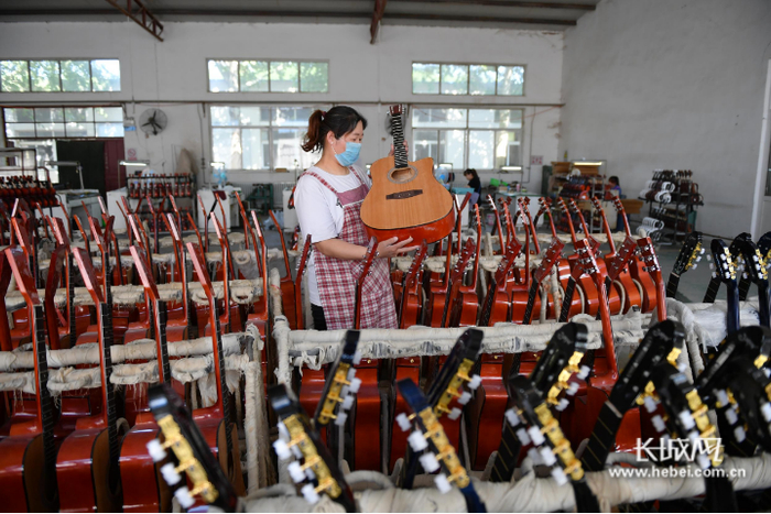 河北金音乐器集团有限公司的工人正在查验吉他质量。
