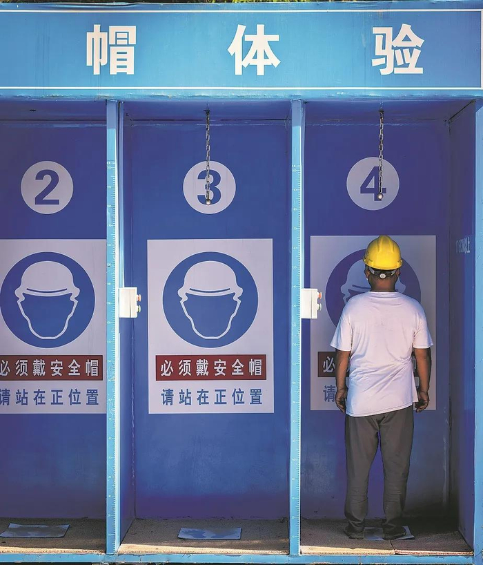 图为一位安全员进入安全帽体验屋，发现屋内并没有通电，模拟重物的钢球悬在半空，“砸”下不来。