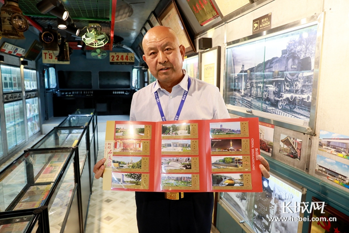 　赵联忠正在展示自己着手设计印制的火车站台票。长城网记者 周亚彬 摄