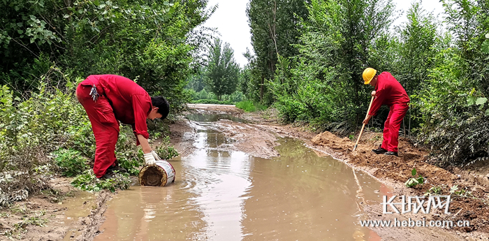 大雨过后，职工们主动清理井场道路积水。候健 李春莲 钱玮玮 摄