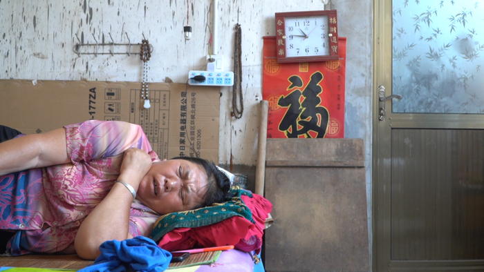  梁秋玉侧躺在床上。图/赵牧 摄