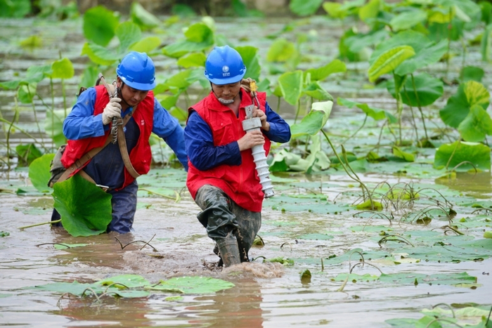 △  队员涉水奔赴变电站开展一体化检修。陈翔 摄