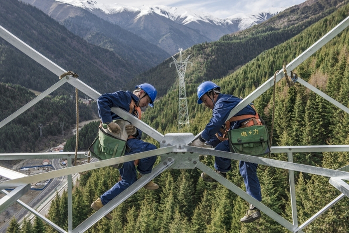 △  队员在“三区三州”电网建设现场进行组塔作业。邹熠霏 摄