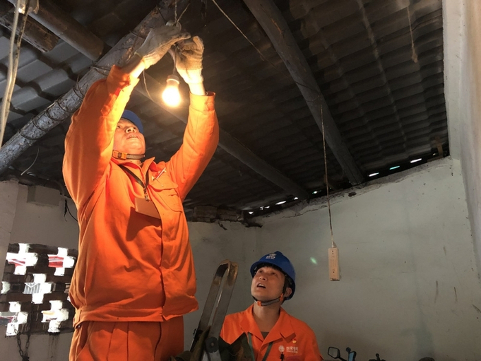 △  队员为社区居民维修供电线路和电灯。李泰运 摄