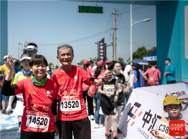 安徽省芜湖市湾沚区半程马拉松比赛中，一对金婚夫妇携手安全完赛，在比赛终点两位老人合影留念，会心一笑。（安徽省芜湖市湾沚区纪委监委 许孝平 摄）