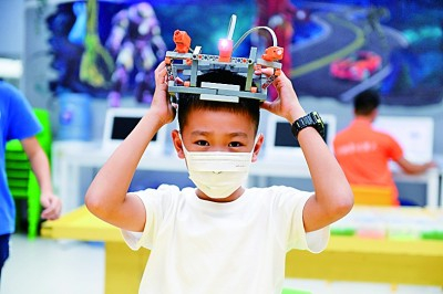 在广东深圳少年宫暑期科技班，小朋友展示拼装的“头灯”。新华社发