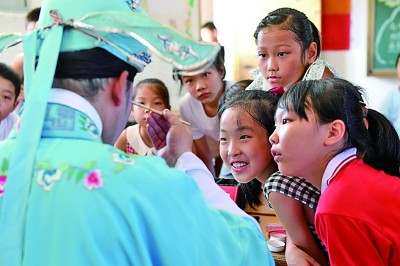 江西宜丰县新昌二小的学生在暑托班观看戏曲老师上妆。周亮摄/光明图片