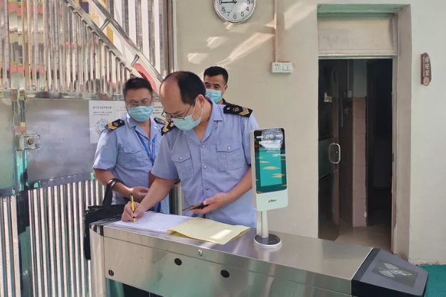 （武江区市场监管局执法人员查看幼儿园疫情防控措施落实情况，并做入园体温检测信息登记。杜丽圆 摄）