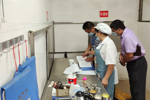 （仁化县市场监管局执法人员查看食堂台账信息。朱东阳 摄）
