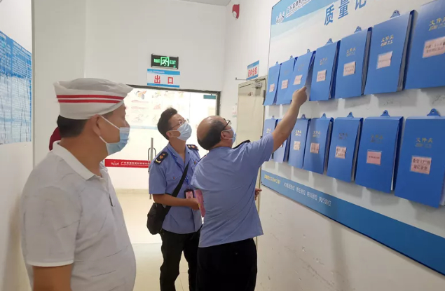 （浈江区市场监管局执法人员查看学校食堂台账信息。邱永锋 摄）