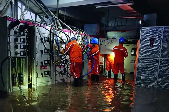 △  抢险保电突击队在郑州建业城市花园小区将保电车低压电缆接入小区配电房，以恢复小区居民用电。摄影/王勇