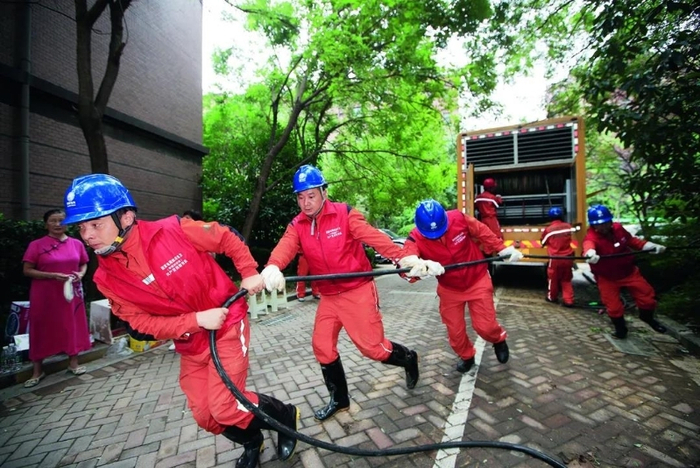 △   四川绵阳供电公司援豫抢修人员在郑州橡树玫瑰城小区搬运应急发电车电缆。摄影/田海
