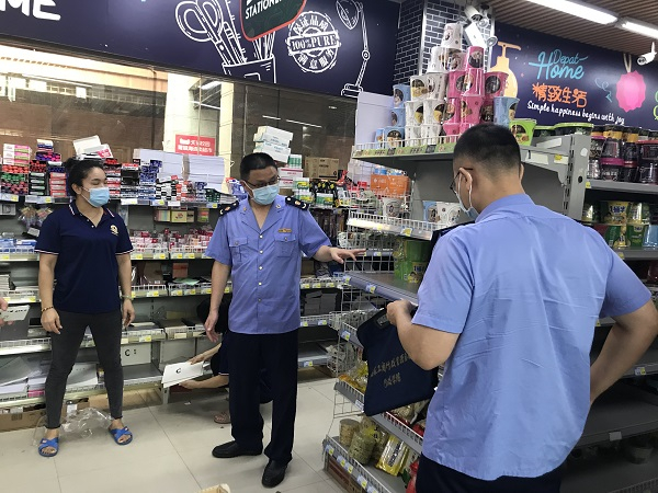 执法人员现场随机抽查超市货架上的商品。
