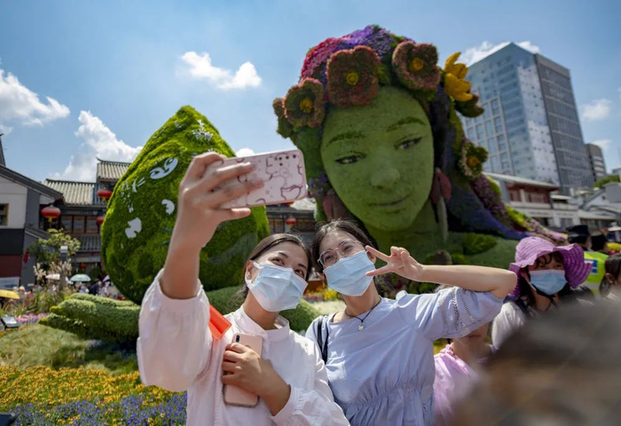 游客在昆明市金碧广场立体花坛前自拍 陈欣波 摄